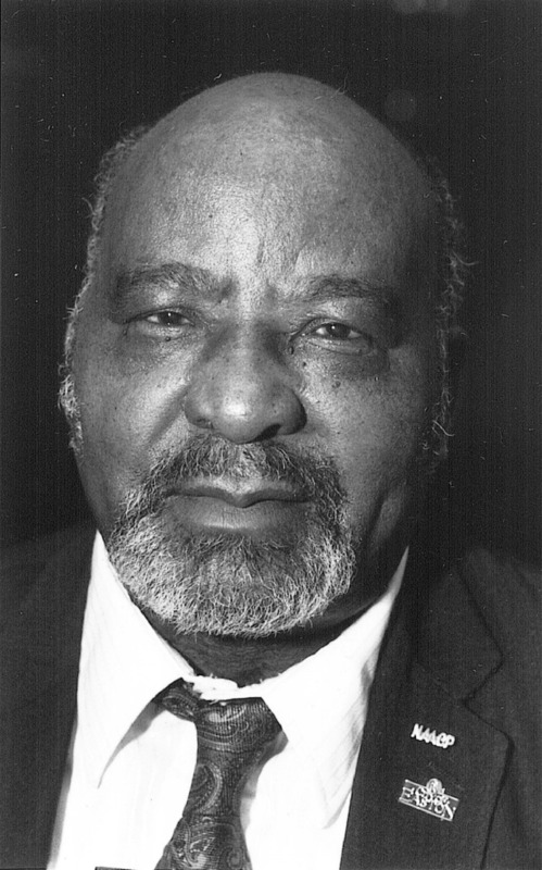 Formal headshot of a man in a formal black jacket and a tie.