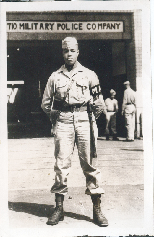 A man in a military police uniform. He is standing in front of a 710th Military Police Company sign.