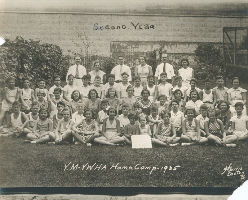 Several children sitting on grass in rows.