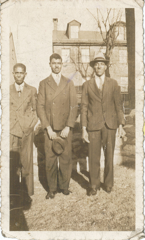 Three men in suits standing.