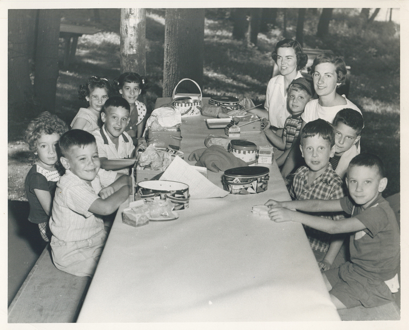 Children sitting at a dining table outdoors.