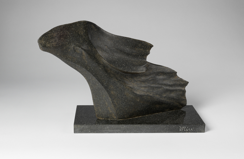 A curved granite sculpture. The underside looks smooth, while the upper surface is rippled and jagged, which resembles a wave. 