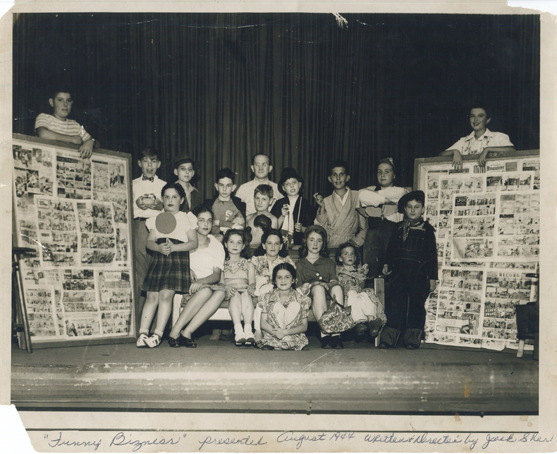 Several children flanked on either side by two individuals holding bulletin boards.