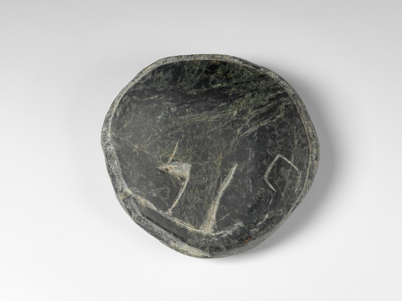 A smooth, round stone with green and black ripples. This side of the stone is carved to look like a simplified, curled up elephant.