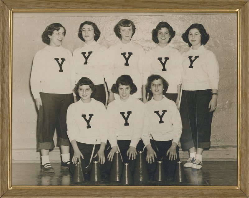 Three girls kneeling while five girls stand behind them. They are all wearing white shirts with the letter "Y" on them.
