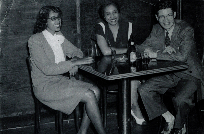 Two women and a man in formal wear sitting at a table.