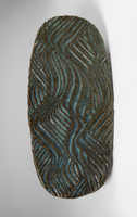 An oblong ceramic slab with repeating wavy lines reminiscent of an abstract hillside carved into it.