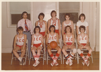 Two rows of teenage basketball players. Team members in the front row are sitting while those in the back are standing.