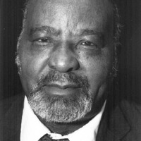 Formal headshot of a man in a formal black jacket and a tie.