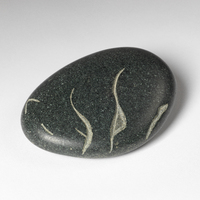 A smooth, speckled oblong stone with a simplistic sleeping bear carved into it. 