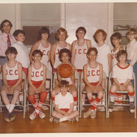 Two rows of boys. They are seated in the front row and standing in the back. Each is wearing a basketball uniform.
