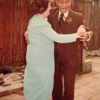 A man in a suit dancing with a woman in a light blue dress.