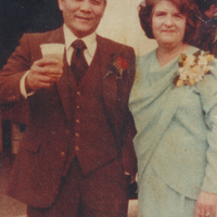 A man in a suit standing next to a woman in a light blue dress.