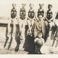Seven boys sitting atop a wall. Each of them is wearing a jersey labeled "T7." A man in a suit stands in front of them.