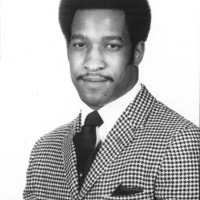 Formal headshot of a man in a houndstooth jacket