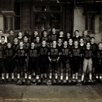 Football players standing in rows in front of a high school building
