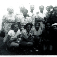Several women gathered in two rows. The women in front are squatting while those behind them are standing.