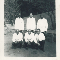 Three men squatting in front of three others that are standing. All six are in uniform.