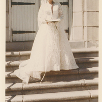 A woman in a white dress standing on a flight of stairs.